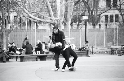 A man dipping a woman while she rides a skateboard in Washington Square Park, NYC. This represents the be there collection of greeting cards by beknown.