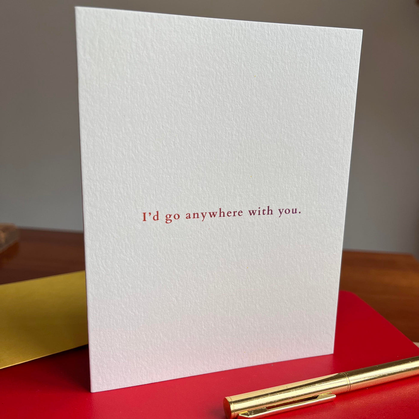 Beknown greeting card on red notebook w/ gold pen. I'd go anywhere with you.