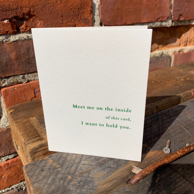 Greeting card on wood table by beknown. Meet me on the inside of this card, I want to hold you.
